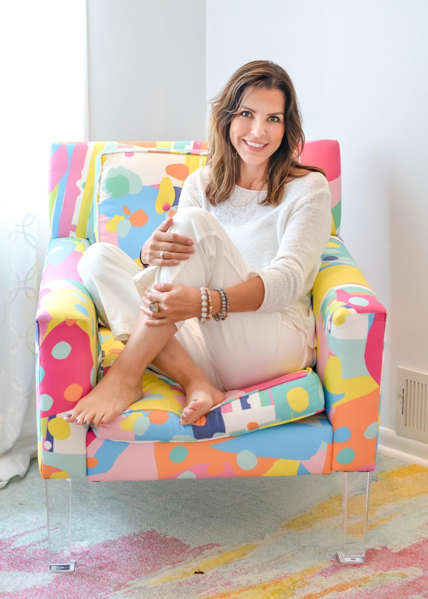 Victoria, founder of The Healing Frequency Space, seated in a colorful chair
